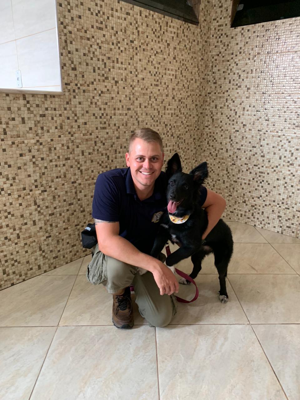 Adestrador com cão preto no ambiente interno